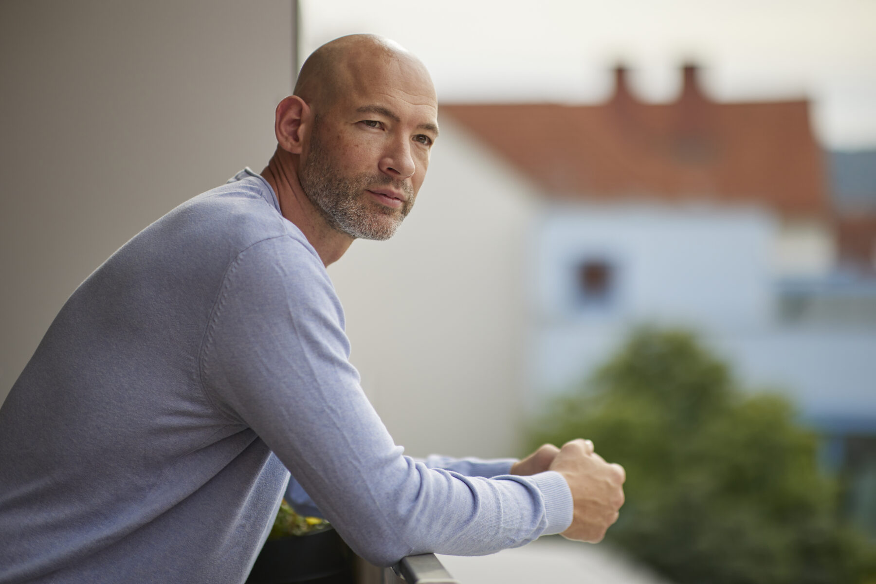 Porträtaufnahme von der rechten Seite: Hannes Lerchbacher, Psychotherapeut in Ausbildung unter Supervision, lehnt an einem Geländer und blickt an der Kamera vorbei.